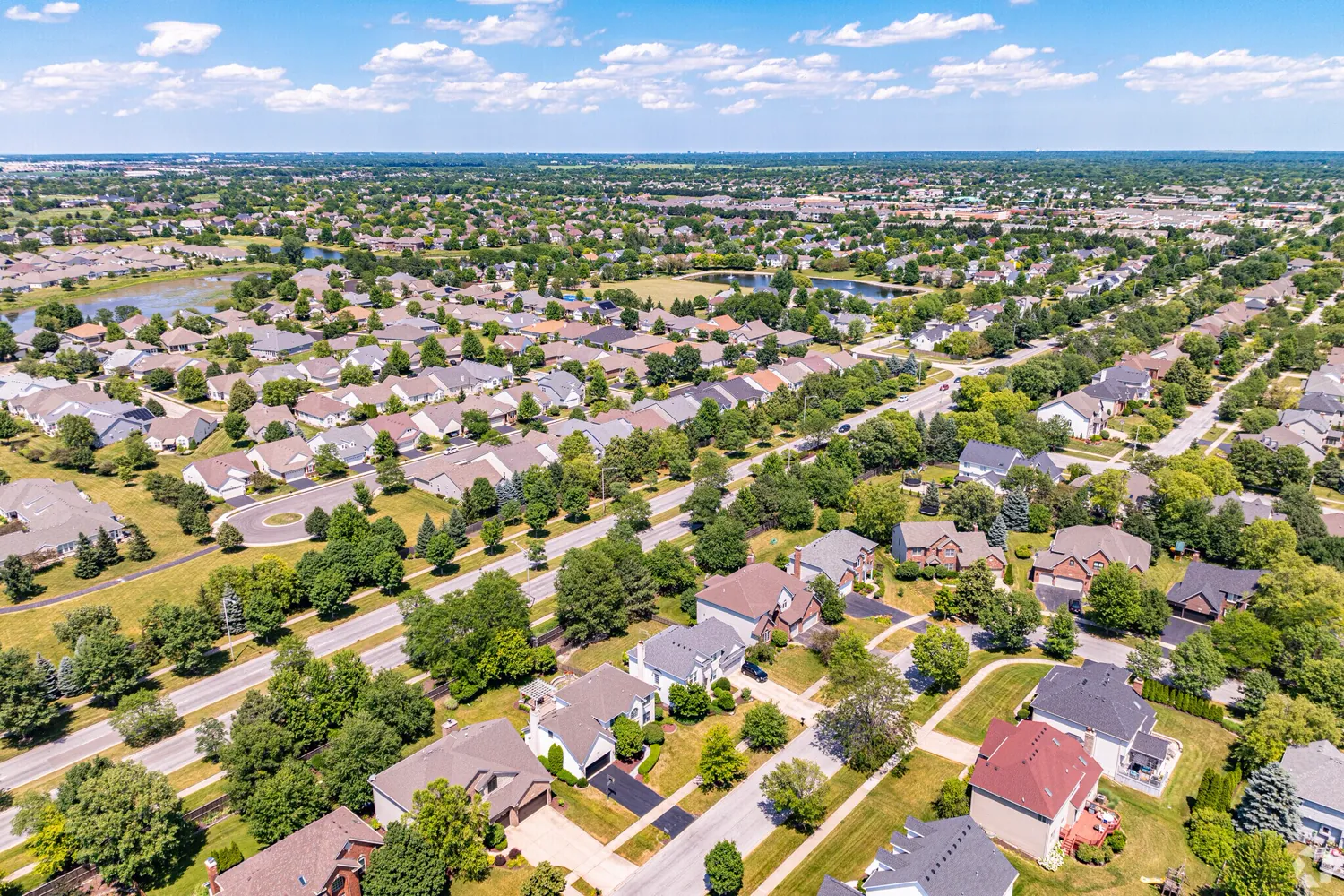 Aerial view of an established western-suburban Chicago residential subdivision with curving streets and ponds